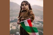 Kind mit kurdischer Flagge in traditionell kurdischer Kleidung