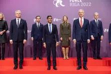 Excerpt from a group photo: Two women and six men stand together on a red staircase in front of a purple wall