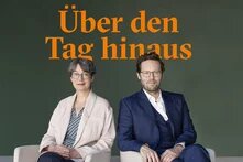 Imme Scholz und Jan Philipp Albrecht sitzend vor dem Schriftzug "Über den Tag hinaus" in orange auf grünen Hintergrund