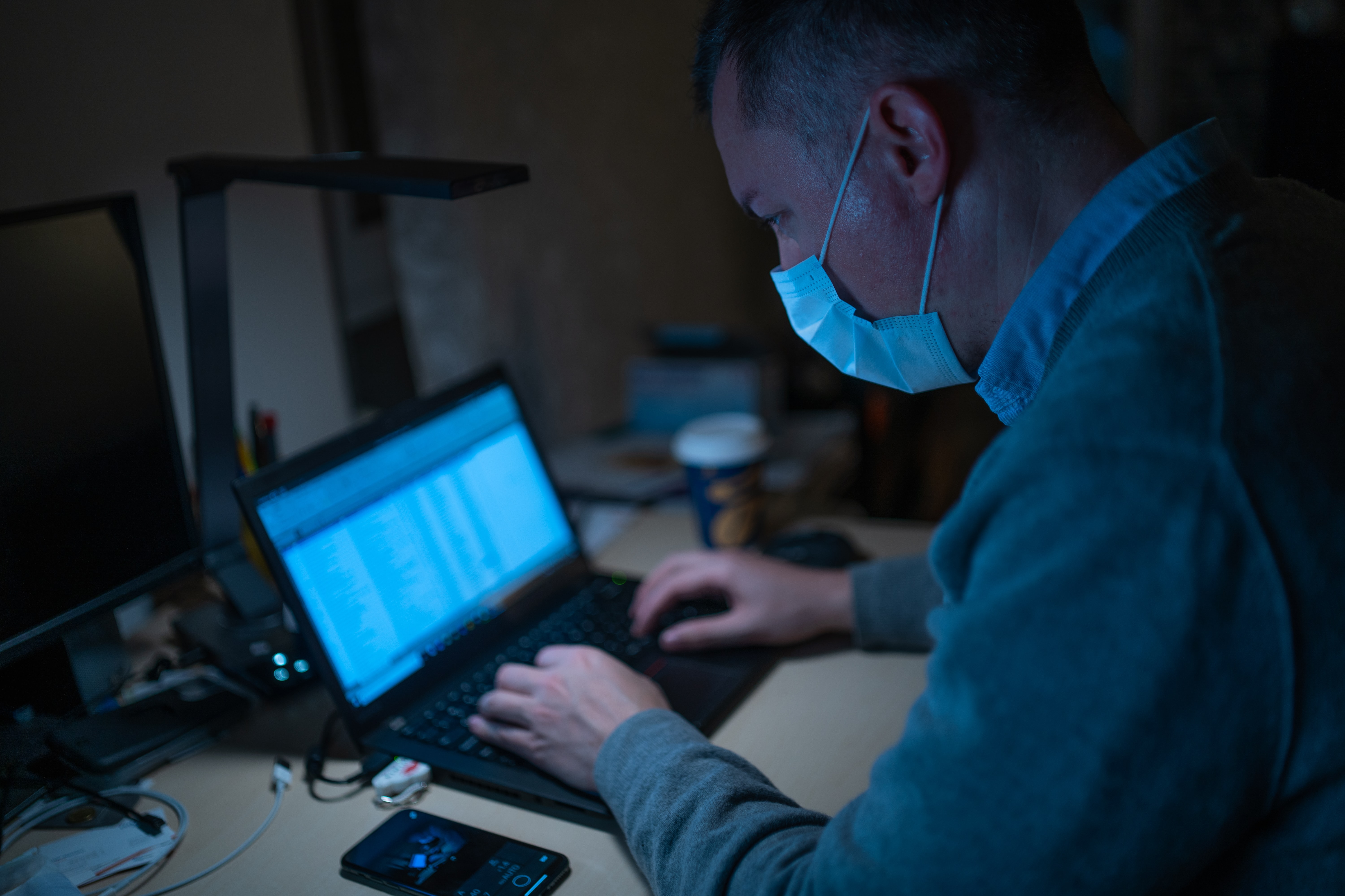 Zukunftsinvestitionen vom Homeoffice Zukunftsinvestitionen in Zeiten der Corona‐Pandemie - Mann mit Mundschutz sitzt vor Computer