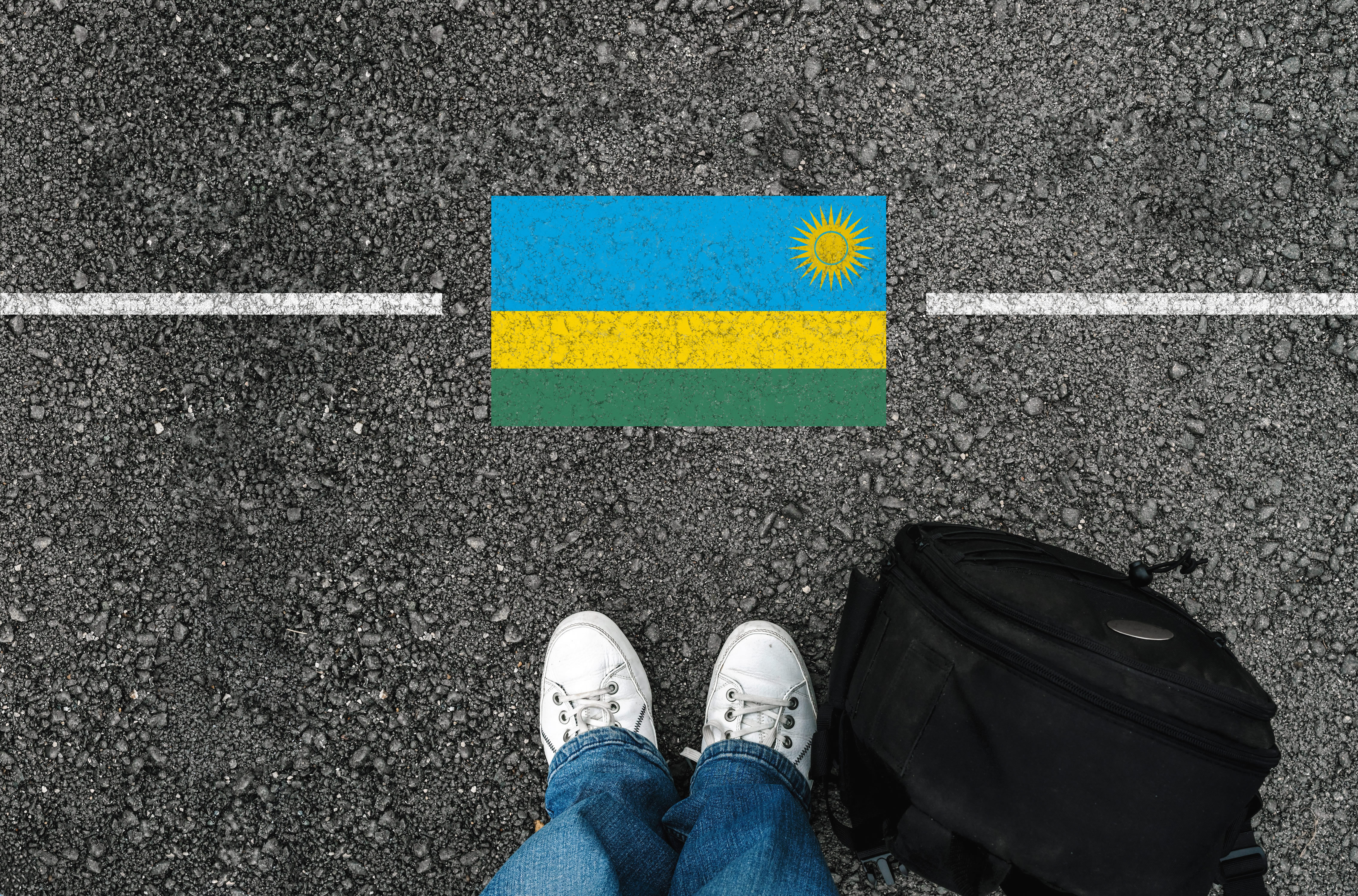 Abschibung nach Ruanda Füße vor eine symbolischen Grenzlinie mit der Flagge des afrikanischen Lands Ruanda