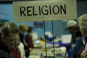 Women in bookshop under a sign reading religion