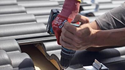 Zwei Personen befestigen ein Befestigungssystem für Solarmodule auf einem Dach. 