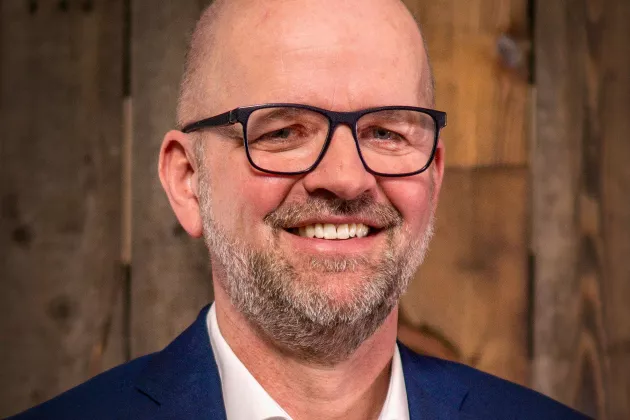 Andreas Rade trägt Brille und blickt lächelnd in die Kamera