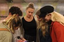 Junge Menschen stehen zusammen und schauen auf ein Handy