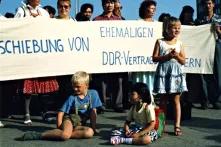 Kinder sitzen vor einem Banner, Demo gegen die Abschiebung von ehemaligen DDR-Vertragsarbeiter/innen