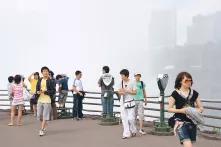 Menschen auf einem Aussichtspunkt, dahinter Smog