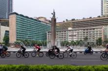 Fahrradfahrende vor der 'Welcome to Indonesia Statue in Jakarta