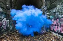 Blaue Rauchwolke zwischen zwei Mauern mit Graffiti