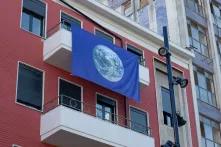 Büro der Heinrich-Böll-Stiftung in Tirana - rotes, mehrstöckiges Gebäude mit am Balkon hängenden blauen Fahne mit Erdkugel