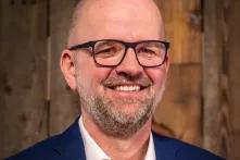 Andreas Rade trägt Brille und blickt lächelnd in die Kamera