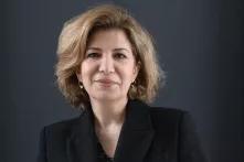 Joumana Seif blickt mit einem Lächeln in die Kamera vor einem dunklen Hintergrund