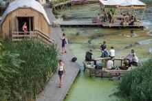 Viele Menschen sitzen auf Bänke im Wasser beim Floating University. Es gibt auch eine Hütte und einen Laufweg über das Wasser