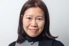 Lucia Siu blickt lächelnd in die Kamera vor einem weißen Hintergrund