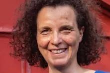 Portrait einer Frau mit braunen Locken vor rotem Hintergrund