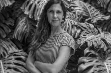Portrait of Carolina Gamazo Aramedia. Black and white image. She is standing among leaves.