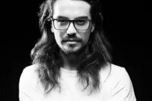 Black and white portrait of Erick Fariñas Torres with long hair and glasses. 