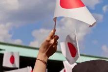 Kleine Japanische Flagge wird von einer Hand hochgehalten. 