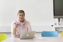Katrin Reimer-Gordinskaya sitzt an einem Tisch mit einem Laptop vor ihr.