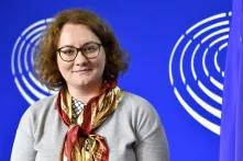 Porträt von Alba Cela mit schulterlangen Haaren und Brille vor einer blauen Wand. 