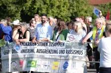 Mehrere Menschen stehen hinter einem Transparent auf dem der Schriftzug "DEMOKRATEN STEHEN ZUSAMMEN GEGEN DISKRIMINIERUNG, AUSGRENZUNG UND RASSISMUS" steht sowie die Logos von CDU, SPD, Bündnis 90/Die Grünen, Freie Wähler, FDP, Offene Liste