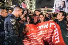 Tel Aviv, Israel: Israelische Polizeibeamte schieben weibliche Demonstrant*innen mit Plakat weg, die die Straße blockieren