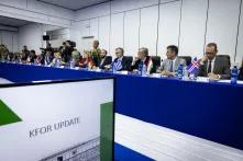 NATO Deputy Secretary General Mircea Geoană and the Ambassadors of Allies and of KFOR troop-contributing Partners sitting on a large blue table