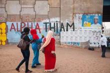 Drei Frauen laufen vor einer Wand mitr Wahplakaten lang. 