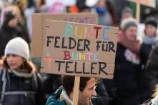 Menschen auf einer Demonstration mit einem Schild, auf dem steht: Bunte Felder für bunte Teller. 