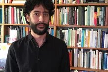 Daniel Hirata steht vor einem Bücherregal