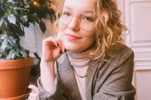 Porträt von Rike van Kleef. Eine blonde Frau mit großer Brille und Blazer lächelt in die Kamera.