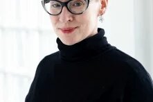 Porträt von Dani Kranz mit schwarzem Rollkragenpullover und Brille. 