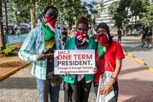 Drei Menschen mit Halstüchern halten ein Schild mit der Aufschrift "Half One Term President. Enough is Enough Zakayo #RejectFinanceBill2024". Sie stehen auf einem Gehweg in Nairobi, Kenya.
