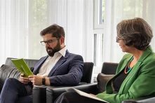 Gabriel Boric, Präsident Chiles, sitzt auf einem dunklen Sofa und hält eine grüne Publikation in der Hand. Neben ihm sitzt Imme Scholz, Vorstand der Heinrich-Böll-Stiftung.