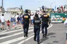 Foto: Paris, drei Polizist*innen in Uniform gehen durch eine Menschenmenge in Richtung Eiffelturm.