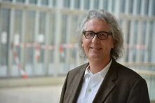 Dr. Reinhard Olschanski, Person in Anzug mit graumeliert, mittellangen Haaren und Brille