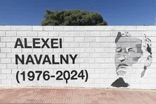 Foto: Wand mit Porträt von Alexei Nawalny und Text „ALEXEI NAVALNY (1976-2024)“, davor Gehweg.