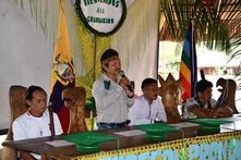 Menschen sitzen und stehen an einem langen Tisch, es sind die Sarakayu, die "Verteidiger:innen des Waldes", in Ecuador. 