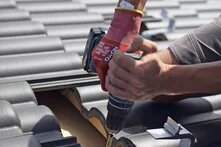 Zwei Personen befestigen ein Befestigungssystem für Solarmodule auf einem Dach. 