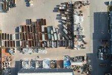 Photo: Aerial view of a junkyard with numerous containers filled with metal and aluminum scrap. Piles and piles of recyclable material.