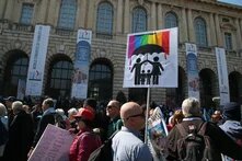Verona, Menschenmenge vor Gebäude mit Transparenten zum World Congress of Families; vorn Plakat mit stilisierter Familie und Regenbogenfarben.