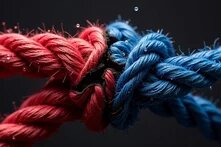 Zwei dicke, miteinander verknotete Seile – eines rot, eines blau – vor dunklem Hintergrund, mit sichtbaren Wassertropfen