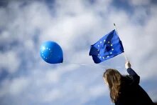 Frau mit EU-Fahne und blauem Luftballon mit Europalogo