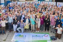 Große Gruppe von Menschen winkt in die Kamera, stehend hinter zwei Bannern mit Aufschrift „Bonn4Future – Wir machen Wandel“.