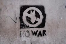 Ein Graffiti zeigt die durchgestrichene Silhouette einer herabfallenden Bombe, darunter die Unterschrift "NO WAR" 