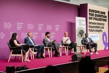 Fünf Podiumsteilnehmende sitzen vor lila Wand beim European Forum Alpbach 2025, rechts Banner und Leinwand zur Palästina-Debatte.