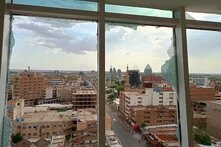 Blick einem kaputten Fenster auf das zerstörte Zentrum von Khartum, Sudan.