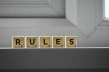 Fünf Spielsteinwürfel mit dem Wort „RULES“ (Regeln) stehen auf einer Fensterbank.