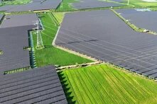 hbs Bildbeschreiber sagte:Large solar panel fields cover most of the landscape, with narrow green crop rows and power lines running through the area.