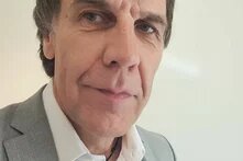 Person mit kurzem Haar blickt in Innenraum leicht seitlich in die Kamera.